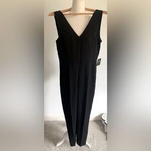 Faltering black V neck in front and back jumpsuit. Wide legs that taper Size S